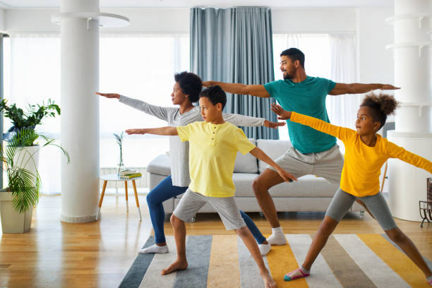 Closeup front view of a young african american family with son and daughter exercising at home during coronavirus quarantine. They are practicing some yoga moves.